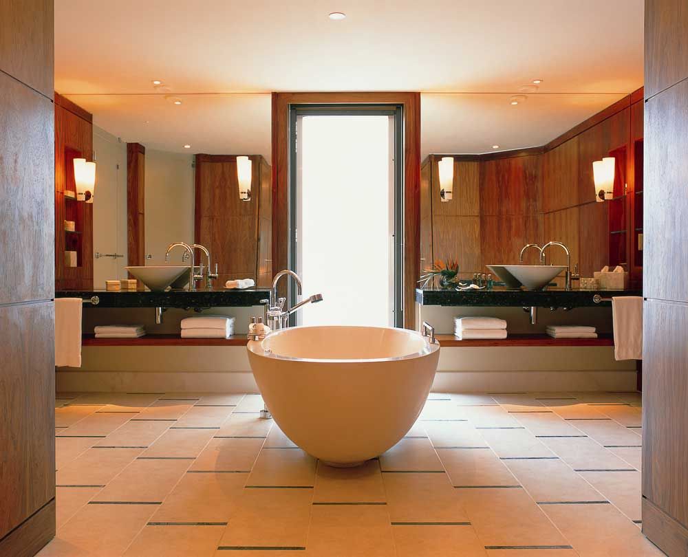 Просторная ванная комната с настенными лампами и большими зеркалами